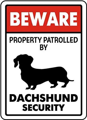 A red and white warning sign that says BEWARE PROPERTY PATROLLED BY DACHSHUND SECURITY