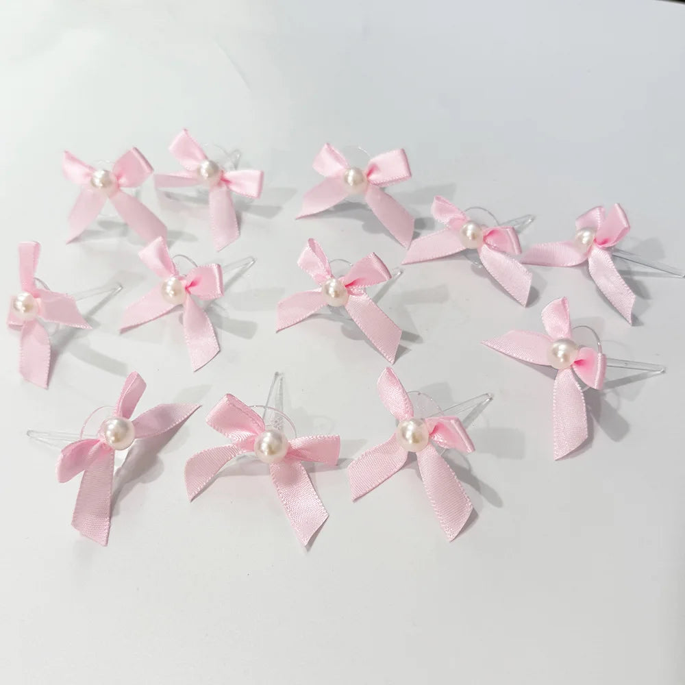 A set of pink satin bow cupcake toppers with pearl accents for birthday and bridal shower decorations.