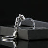 Llavero de cadena plateada con dije de corazón de cristal transparente sobre una caja negra.