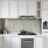 Modern kitchen cabinetry featuring light gray marble pattern backsplash and white cabinets.