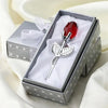 A silver crystal rose artificial flower in a box with white tissue paper and a red gemstone, set for home decor.