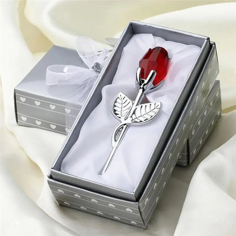 A silver crystal rose artificial flower in a box with white tissue paper and a red gemstone, set for home decor.