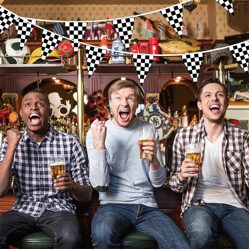 Trois hommes rient en tenant des verres de bière dans un bar avec des drapeaux à carreaux au-dessus