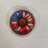 A challenge coin featuring a sunflower design with American flag elements and dark background.