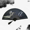 A black hand carved bamboo folding fan with white and gray designs against a white background.