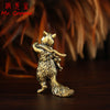 A vintage brass squirrel figurine standing on a dark wooden surface.