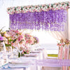A wedding setup featuring a floral backdrop with purple wisteria hanging flowers over a table.