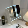 A tri-fold LED makeup mirror with dimmable lighting is displayed on a white surface.