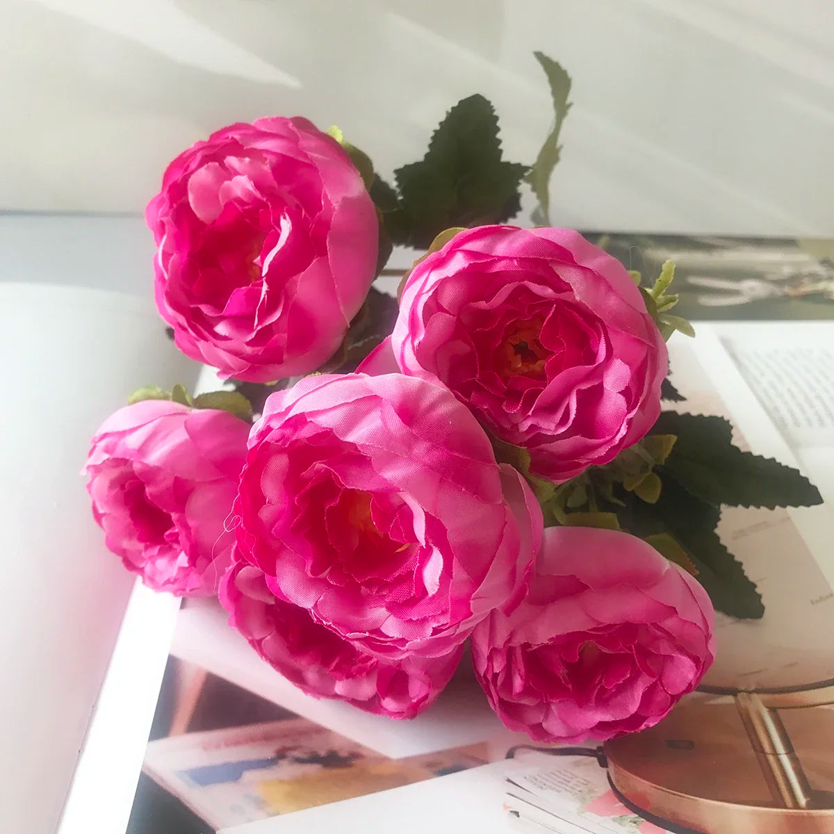 A bouquet of vibrant pink silk rose and peony artificial flowers displayed on a white surface.