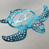 A teal metal sea turtle wall art cutout featuring intricate scale patterns and ocean wave designs.