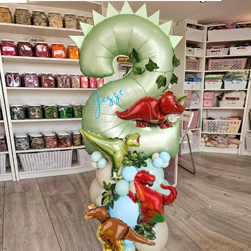 Ein großes grünes Ballon in Form der Zahl 3, dekoriert mit roten Dinosaurierblättern und Früchten.