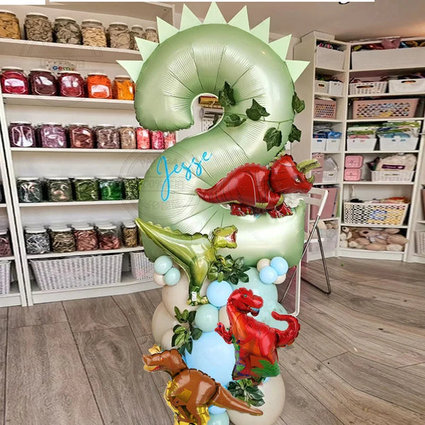 A large green balloon shaped like the number 3, decorated with red dinosaur leaves and fruit.