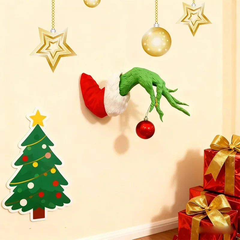 Wall decor featuring a green monster arm and Christmas ornaments on a cream-colored wall.