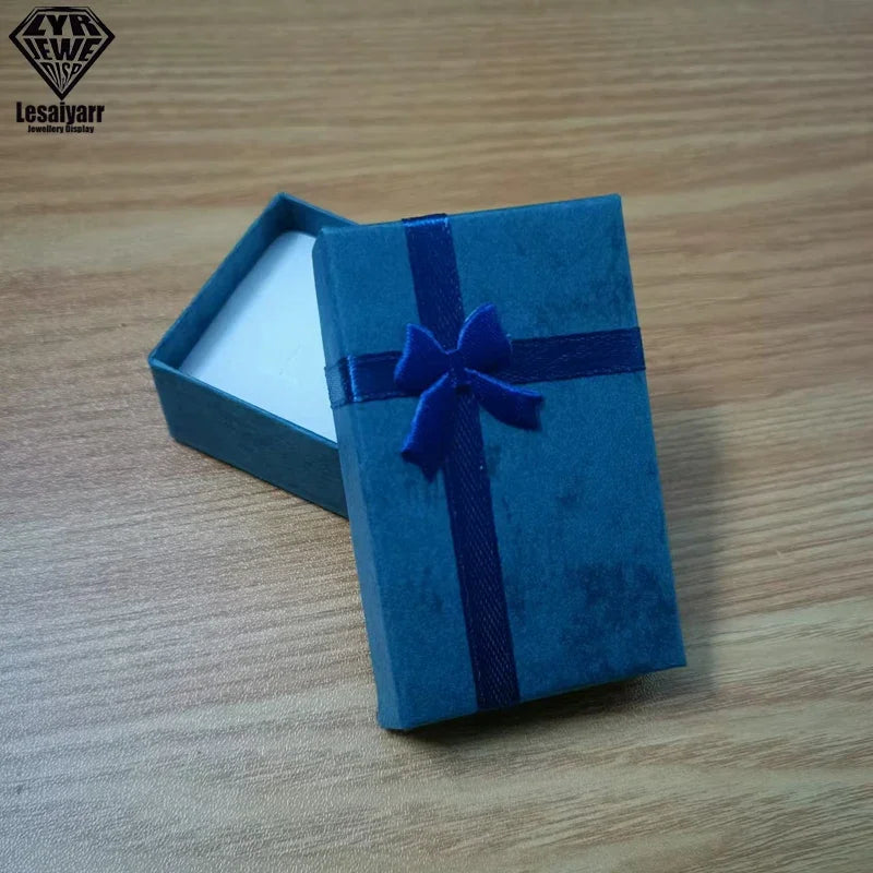 Caja de regalo rectangular de terciopelo azul atada con una cinta azul oscuro, sobre una superficie de madera.