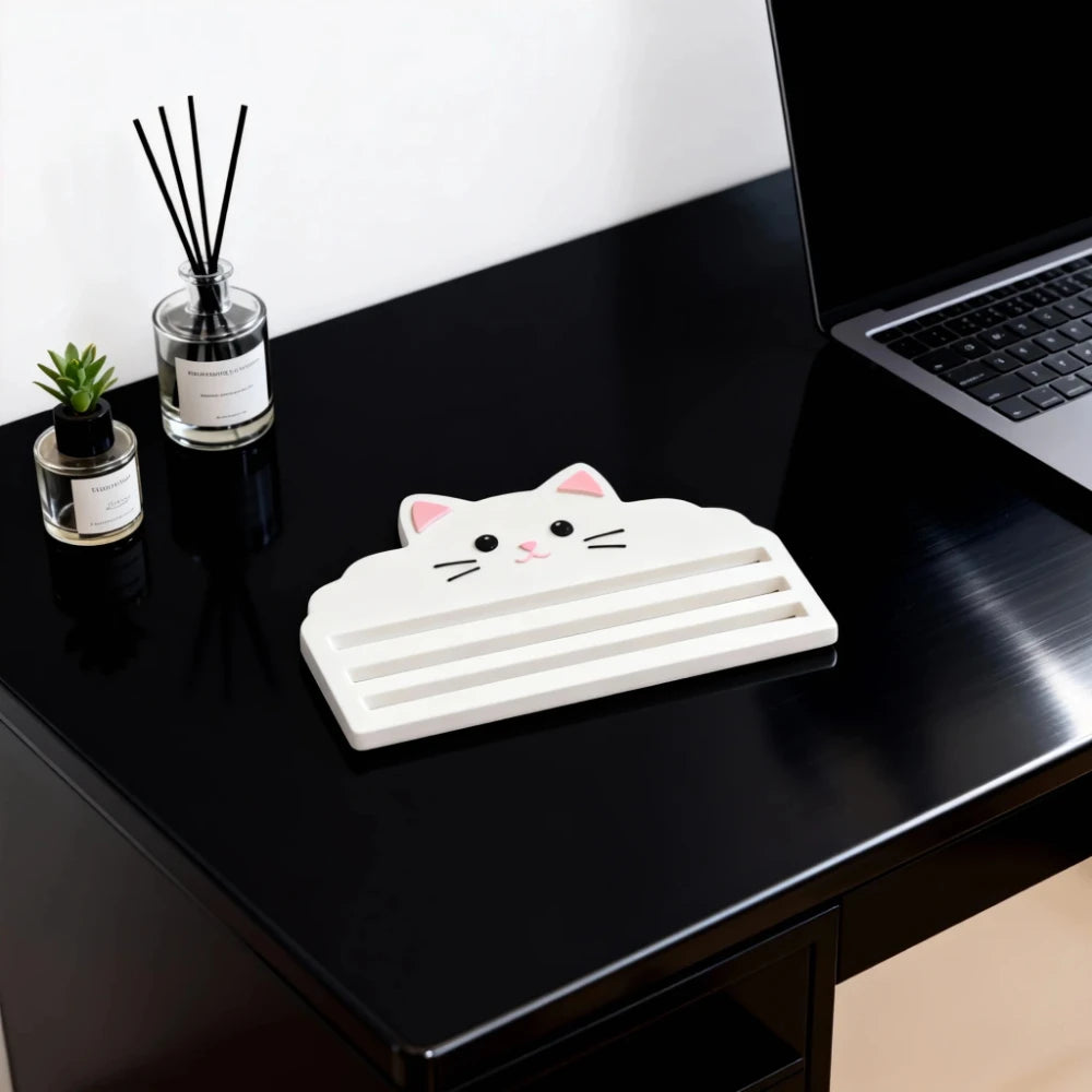 A white cat-shaped squeezer tool for dispensing cat food placed on a black desk.