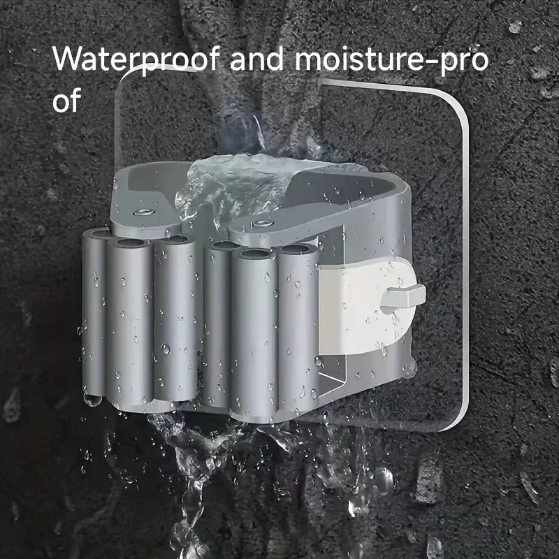 A wall-mounted holder for a mop and broom, made of silver plastic, is shown against a dark background.