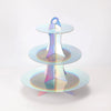 A three-tier rainbow colored cupcake stand with iridescent plastic cups for dessert displays.