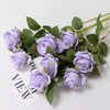 A bouquet of purple velvet artificial roses with green leaves shown from a top view.