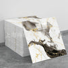 A stack of faux marble 3D self-adhesive wall tiles in gold and black marble pattern on a gray surface.