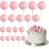 A display of pink foam ball cake toppers on pink sticks, ready for party decorations.