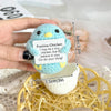 Hand holding a light blue crochet positive chicken doll with an inspirational slogan and a small pocket.