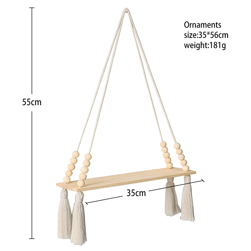A rustic wooden wall shelf with hanging ornaments made of natural fiber strings and tassels.