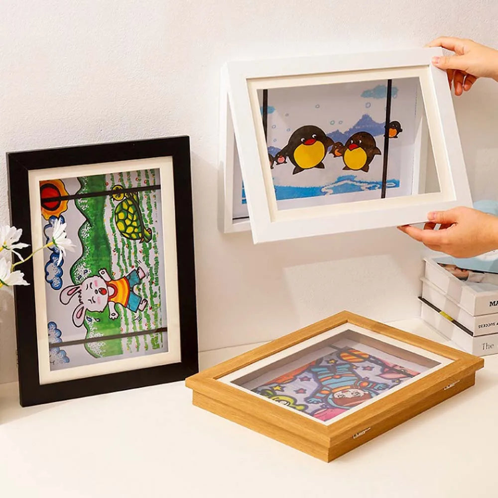Two magnetic front opening art display frames are shown, one hanging on a wall and one lying flat.