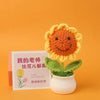Handmade knitted orange and yellow sunflower flower in a white pot on an orange background