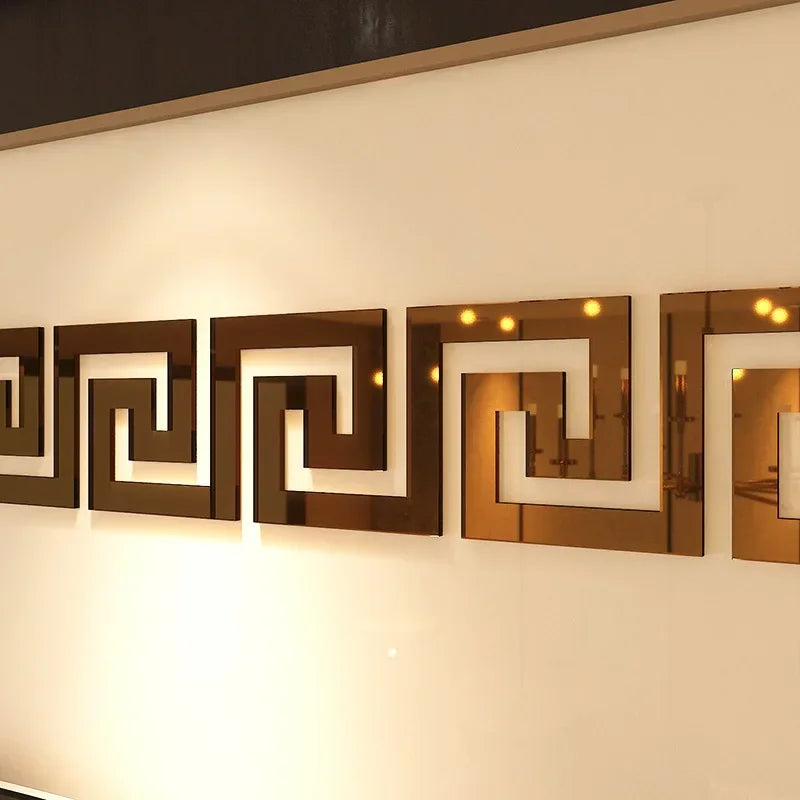 A row of decorative acrylic mirror wall stickers featuring geometric edge and corner trim in bronze and gold tones.