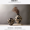 A black and white ceramic vase with a geometric circle pattern displayed on a light surface.