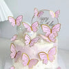 A white cake decorated with pink butterfly toppers and a gold circle sign reading Happy Birthday