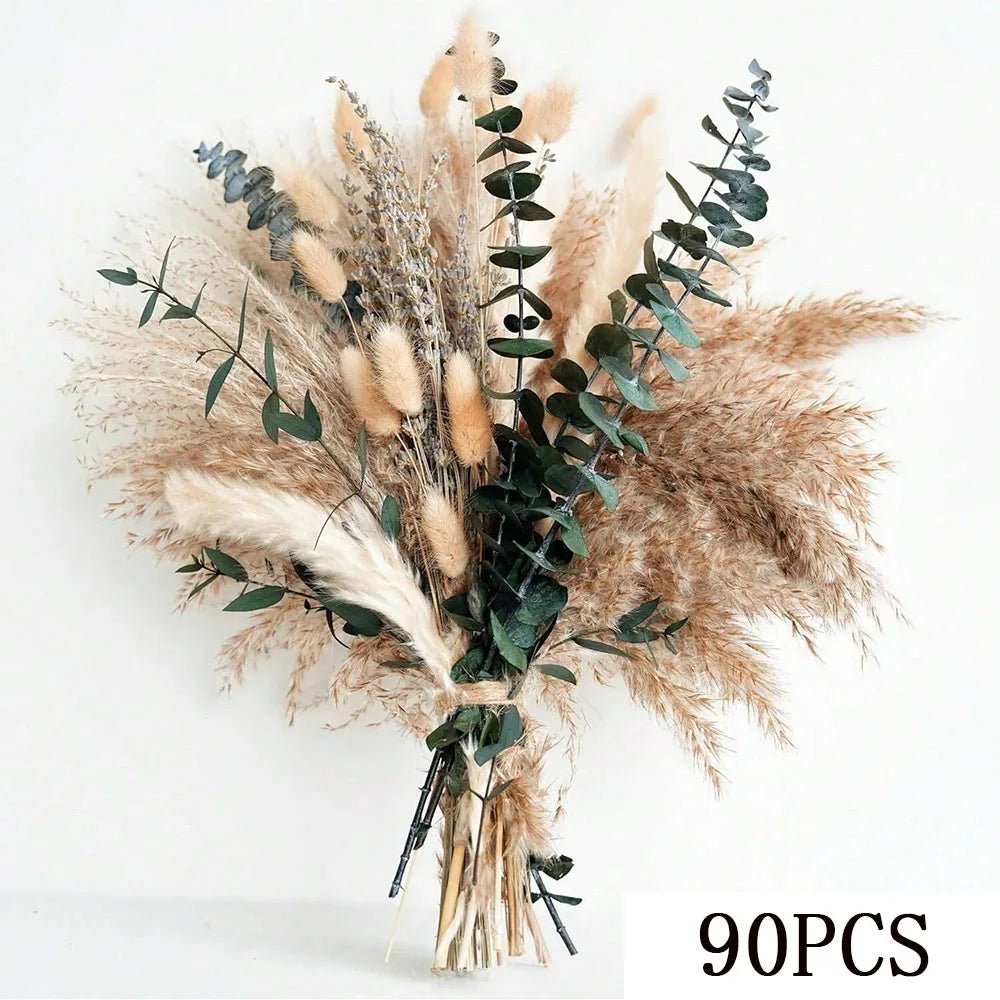 A dried floral bouquet featuring feathery pampas grass and eucalyptus leaves in neutral beige and green tones.
