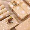 Several gifts wrapped in kraft paper with white snowflake patterns and natural greenery