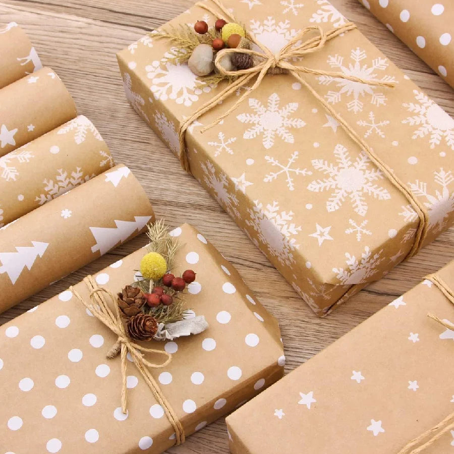 Several gifts wrapped in kraft paper with white snowflake patterns and natural greenery