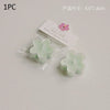 A single light green flower-shaped soy wax tea light candle in clear packaging with a pink label.