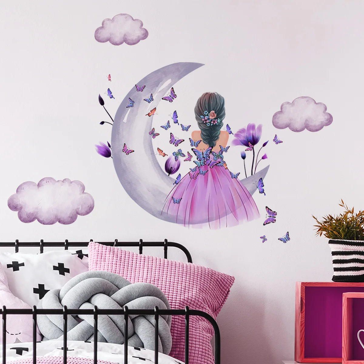 Décor mural avec une grande lune en croissant et des papillons sur un mur blanc au-dessus d'un lit.
