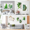 A display of framed diamond art and photos on a white wall, featuring green foliage and natural elements.