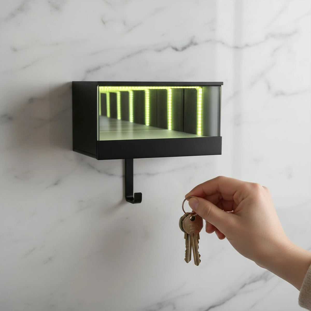 A hand is holding a gold-colored keychain with a loop, positioned near a black wall-mounted light fixture featuring an illumi