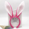 Pink bunny ear headbands displayed on a white photo frame with lavender foliage.