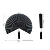 A black handwoven bamboo wall fan decor with a tassel, shown flat and with a hanging cord.