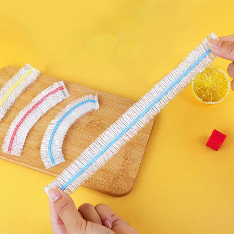 A hand holds a white and blue reusable elastic food cover for bowls or containers on a wooden cutting board.