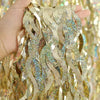 Close-up of gold laser wavy foil fringe curtain decor fabric being held by a hand.