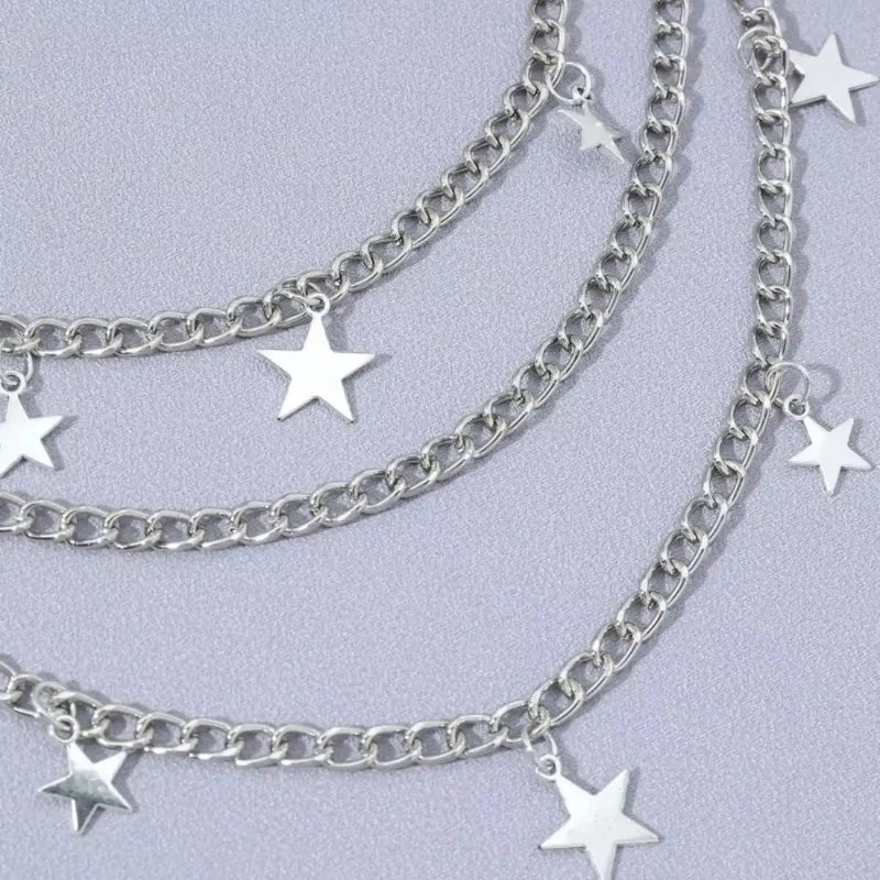 Silver Y2K star charm layered chain necklace displayed against a light purple background.