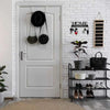 A white door features a metal key holder with wall mounted hooks and decorative plants on the surrounding brick wall.