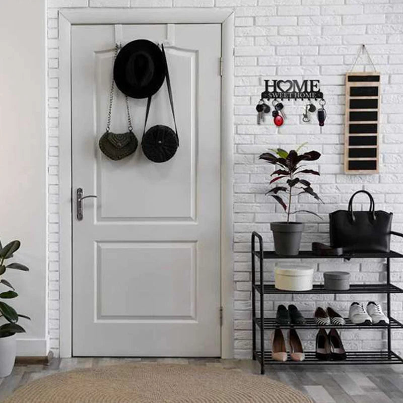 A white door features a metal key holder with wall mounted hooks and decorative plants on the surrounding brick wall.