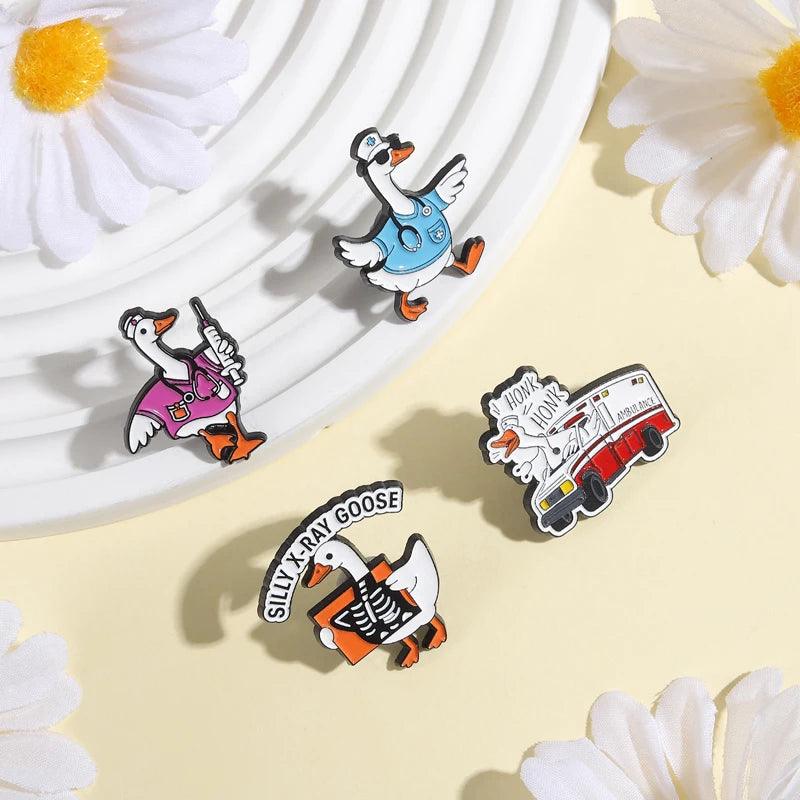 A set of enamel pins featuring cartoon geese and flower designs on a light background.