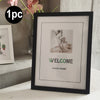 A black photo frame with a white mat displaying the word WELCOME and PHOTO FRAME text.
