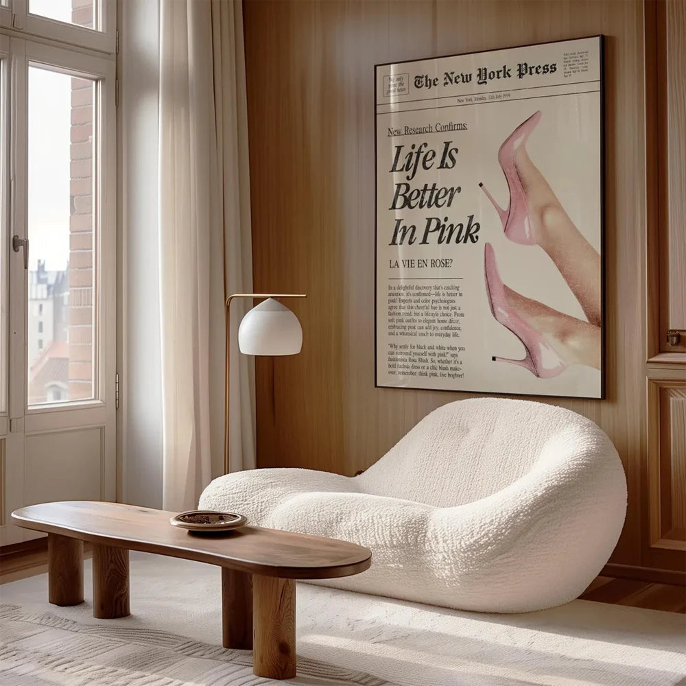 A white, textured armchair sits next to a wooden coffee table in a warmly lit room with a framed print of Life Is Better in P