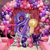 A large purple number balloon and various pink and purple balloons arranged in an archway decoration.