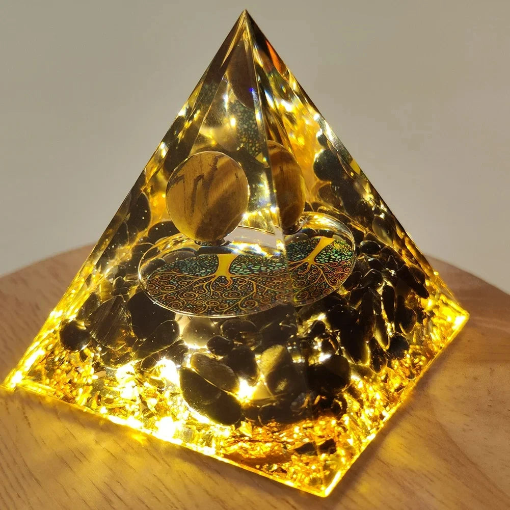 Handmade resin orgonite pyramid with natural obsidian and copper coil resting on wood